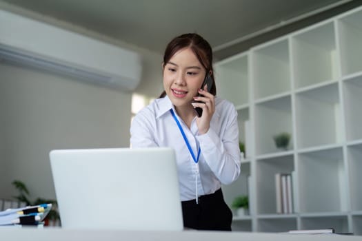 Attractive young business woman professional talking on the mobile phone and standing at working place in office.