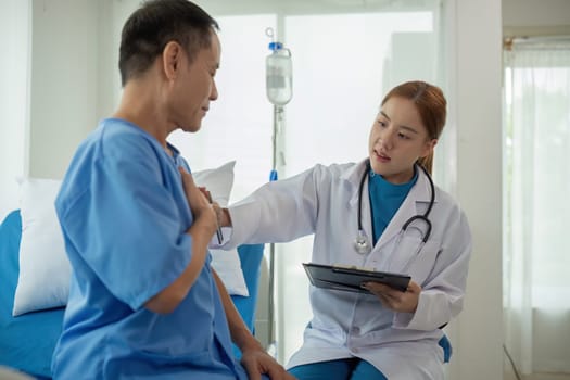A doctor is talking to a patient in a hospital room. The patient is wearing a blue hospital gown