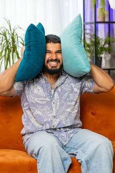 Repair work at neighbors. Irritated man cover ears with pillows annoyed by noisy loud music neighbors suffer from headache wishes silence. Thin walls at home flat without sound insulation. Vertical