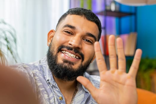 POV view of Indian young man blogger taking selfie on smartphone communicating video call online with subscribers recording stories for social media. Bearded Arabian guy holding mobile phone with hand