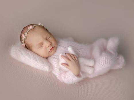 Newborn Girl In Pink Suit Sleeps With Toy Cat During Professional Newborn Photoshoot