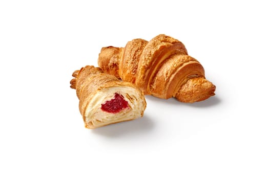 Whole and sliced flaky delicately sweet croissants with berry jam filling, isolated on white background. Modern confectionery in classic French tradition