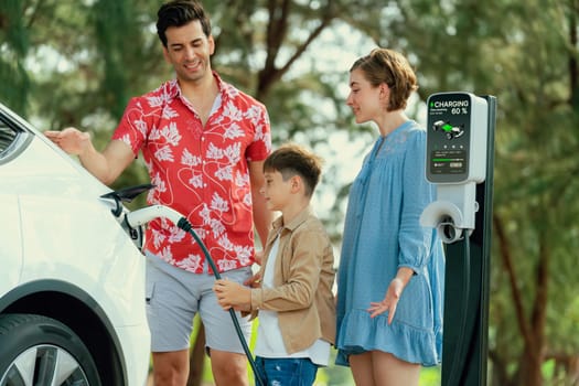 Outdoor adventure and family vacation camping in nature travel by eco friendly car for sustainable future. Lovely family recharge EV car with EV charging station in campsite. Perpetual