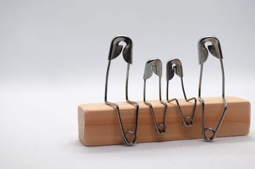 Model safety pin of family sitting on wooden block with customizable space for text.