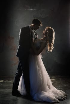 Cute wedding couple in the interior of a classic studio. They kiss and hug each other.