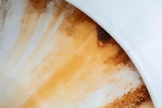 A close-up view of a ceramic white bowl with brown accents. The bowl appears to be empty and is sitting on a flat surface, showcasing its intricate design and color contrast.