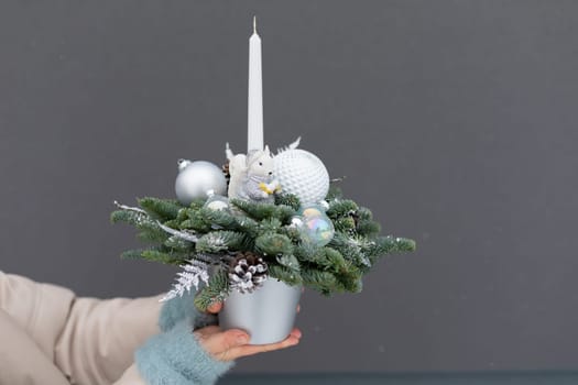 A person is holding a potted plant containing a candle, showcasing a unique decorative element. The individuals hands gently support the pot, emphasizing the combination of greenery and lighting in the composition.