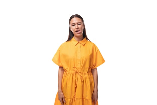 a young woman dressed in a summer yellow dress makes a grimace on a white background.