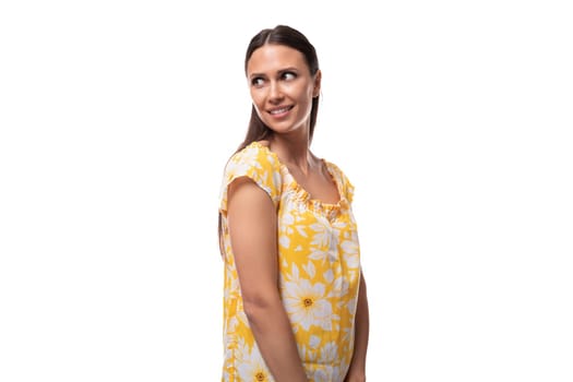 Caucasian young woman with straight black hair smiles welcomingly on a white background.