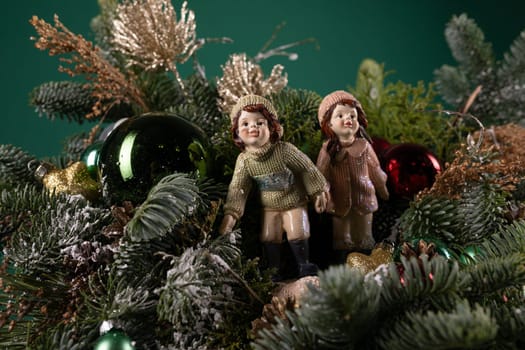 Two figurines, one male and one female, are positioned on the highest point of a beautifully decorated Christmas tree. The couple is wearing festive attire and appear to be holding hands, adding a charming touch to the holiday display.