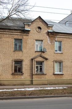 A landmark brick building with intricate brickwork and wooden fixtures, featuring windows and a facade, set against a backdrop of a tree