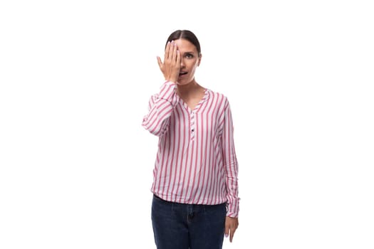 young brunette business woman dressed in a striped shirt looks at the camera on a white background.