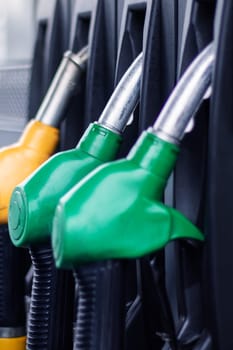 A collection of electric blue, plastic gas pumps, lined up in a row, connected by cables and wires. Each pump is equipped with electronics accessories in shades of carmine