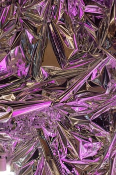 Closeup of crumpled aluminum foil with purple lights resembling a terrestrial plant, creating a magenta and electric blue glow, resembling a fashion accessory or spice