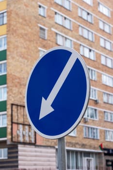 a blue and white sign with an arrow pointing to the right in front of a building . High quality