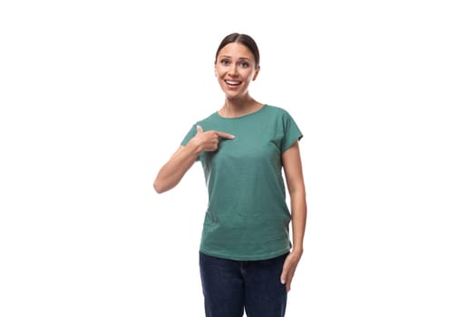 active smiling young caucasian brunette woman in a green t-shirt points with her hand at the space for advertising.