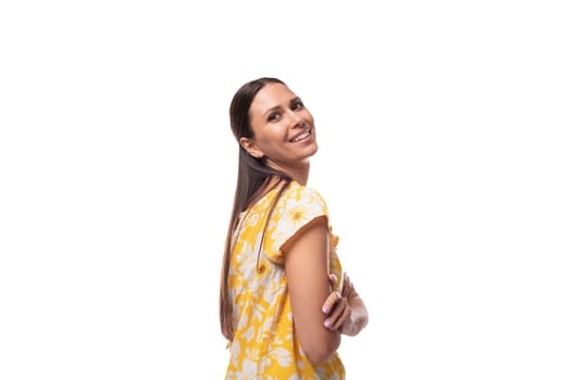 caucasian pleasant cute young woman with straight black hair dressed in a yellow sundress.