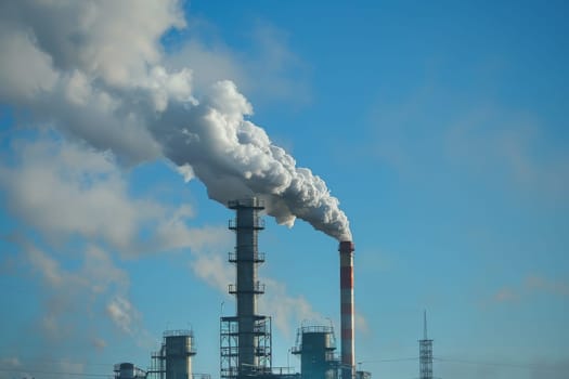 A large industrial plant with a tall stack of smoke coming out of it. The sky is blue and there are birds flying in the background