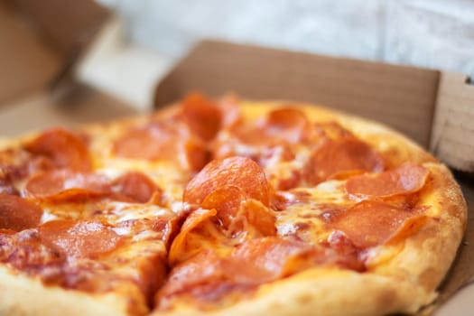 A pepperoni pizza, a staple food in fast food cuisine, rests in a cardboard box. This baked goods dish is a classic recipe of Californiastyle pizza