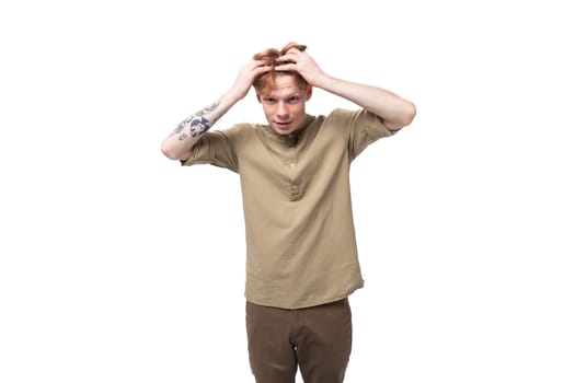 portrait of a handsome young caucasian man with red hair and a tattoo on his arm dressed in a khaki shirt.