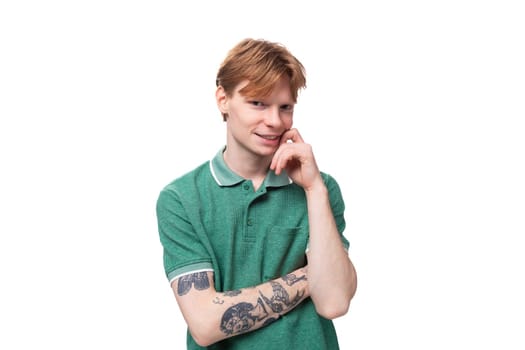 a young european man with red hair and a stylish hairstyle is dressed in a summer green collared t-shirt.