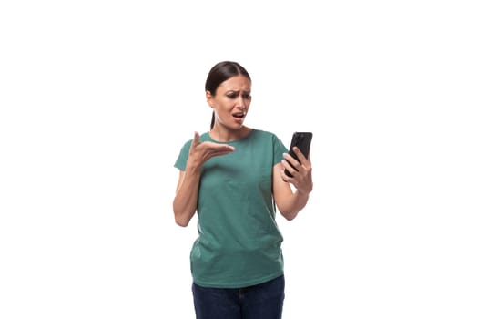 attractive young caucasian woman with black hair in a t-shirt looks attentively at the phone.