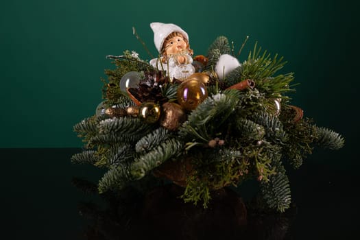 A Christmas arrangement featuring greenery and assorted ornaments beautifully displayed on a table. The greenery includes pine branches, holly leaves, and mistletoe, while the ornaments range from shiny baubles to glittering stars.