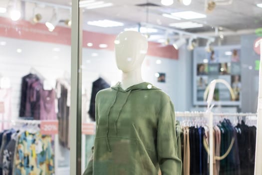 A fashion design mannequin is elegantly displayed in a store window of a boutique, showcasing the latest trendy styles to attract potential customers