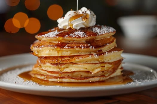 A stack of pancakes with syrup and whipped cream on top. The pancakes are piled high and look delicious