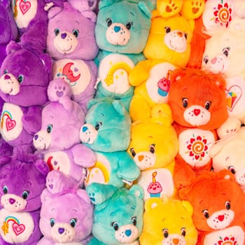 tokyo, japan - apr 16 2024: A cluster of vibrant Care Bears plushies, each embellished with endearing belly badges such as hearts, suns, cupcakes, moons, and rainbows, crafted by Elena Kucharik.