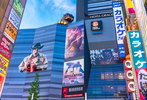 tokyo, japan - apr 28 2024: Facade of the Shinjuku Toho cinemas overlooked by a head of Godzilla and featuring posters and stickers of the Japanese Netflix film "City Hunter" and movie Godzilla - Kong