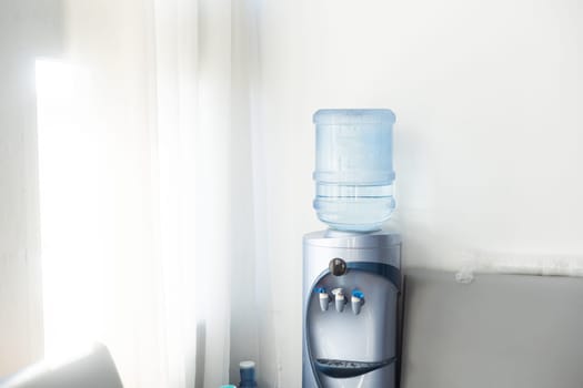 Blue water gallon on water cooler in office