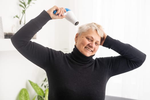 Portrait of senior woman with hair dryer.