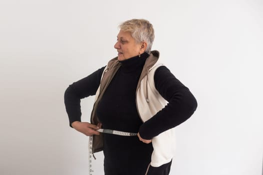 an elderly woman is measured with a tape measure.