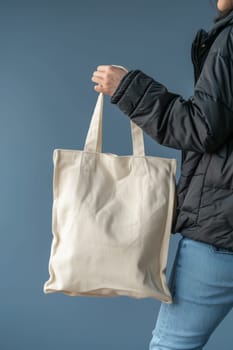 A woman is holding a white canvas tote bag. The bag is plain and unadorned, but it is a blank canvas for the woman to fill with her own personal style and creativity