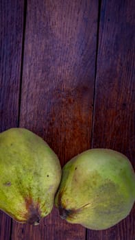 Isolated quinces. Two yellow quinces on a wooden board.