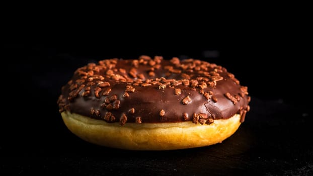 Chocolate glazed donut with chocolate chips isolated. Close up of delicious donut.