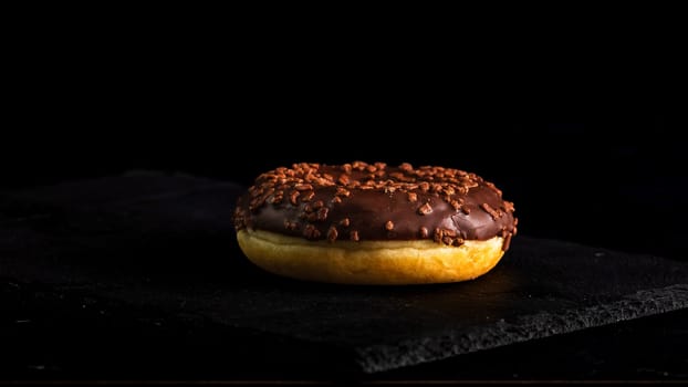 Chocolate glazed donut with chocolate chips isolated. Close up of delicious donut.