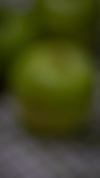 Out of focus, green apples on rustic table napkin.