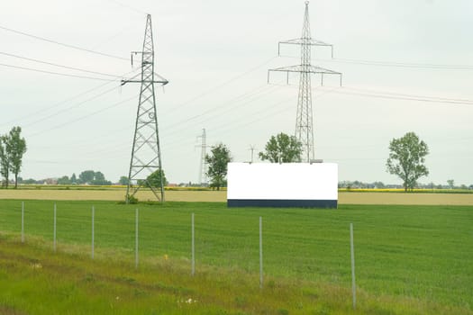 A large billboard standing prominently on the side of the road, displaying a mockup banner to passing drivers and pedestrians.
