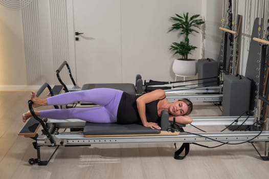 Caucasian pregnant woman doing Pilates exercises on a reformer machine