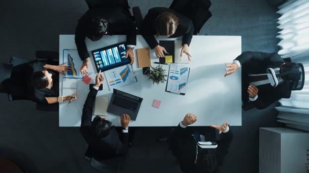 Top view of smart manager give vr head set to businesspeople while businesswoman prepare data analysis or analytic graph in laptop at meeting. Startup team preparing to enter meta verse. Directorate.