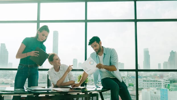 Group of happy skilled businesspeople discuss, brainstorming, sharing idea, plan, strategy about financial statistic on meeting table with laptop and statistic document. Cityscape view. Tracery