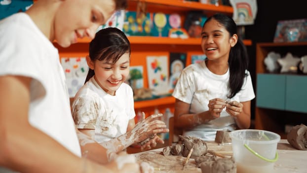 Caucasian highschool girl modeling cup of clay while looking smart boy in art class at workshop. Multicultural student playing or making cup of clay art in creative activity. Education. Edification.