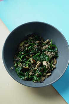 Top view of bowl with cooked spinach on table.