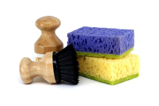 Sponges, each a different color purple, yellow and two brushes with wooden handles isolated on white background, cleaning tools
