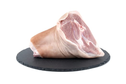 Fresh raw pork shank on black stone plate over white background