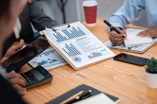 Multiracial analyst team use BI dashboard data to analyze financial report on meeting table. Group of diverse business people utilize data analysis by FIntech for business marketing decision. Concord