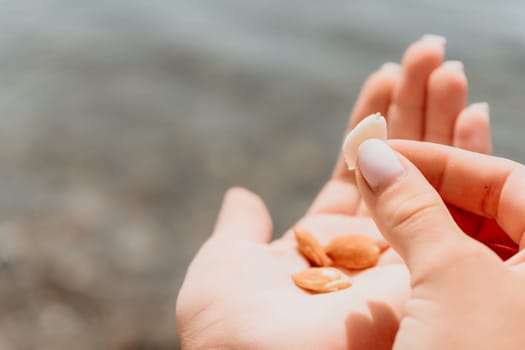 Woman eating milky almond nuts. A young caucasian woman choping fresh green almond after morning fitness yoga near sea. Only hands are visibly. Healthy vegan food. Slow motion. Close up