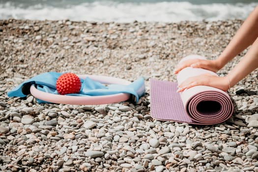 Young woman with long hair in white swimsuit and boho style braclets practicing outdoors on yoga mat by the sea on a sunset. Women's yoga fitness routine. Healthy lifestyle, harmony and meditation